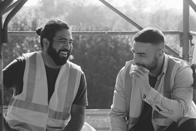 People working in construction site  Men at work in new housing project  Team of happy workers laughing, talking and eating snack during lunch break