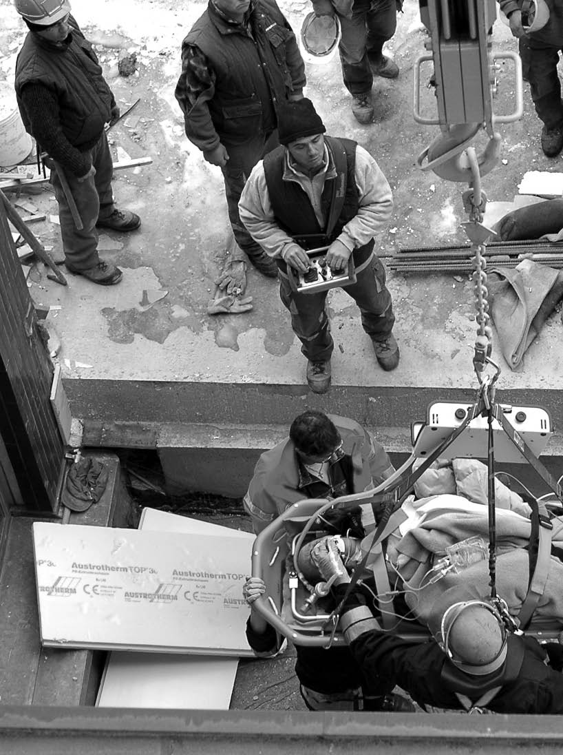 BOLZANO - ITALY, FEBRUARY 2, 2014: Firefighters and paramedics rescue a construction worker after crash  Male worker lying on the floor outside areal of a building site in Bolzano in February 2, 2014