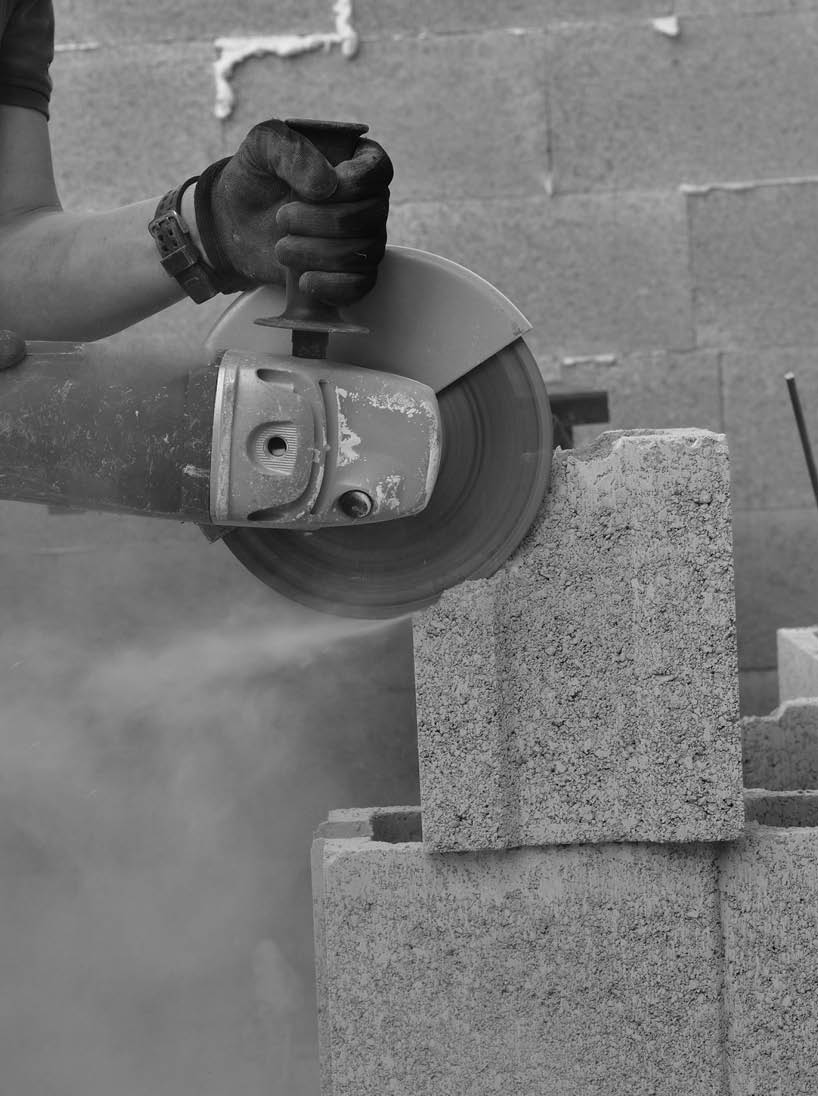 View of a mason's hands on a construction site sawing a block using an electric grinder