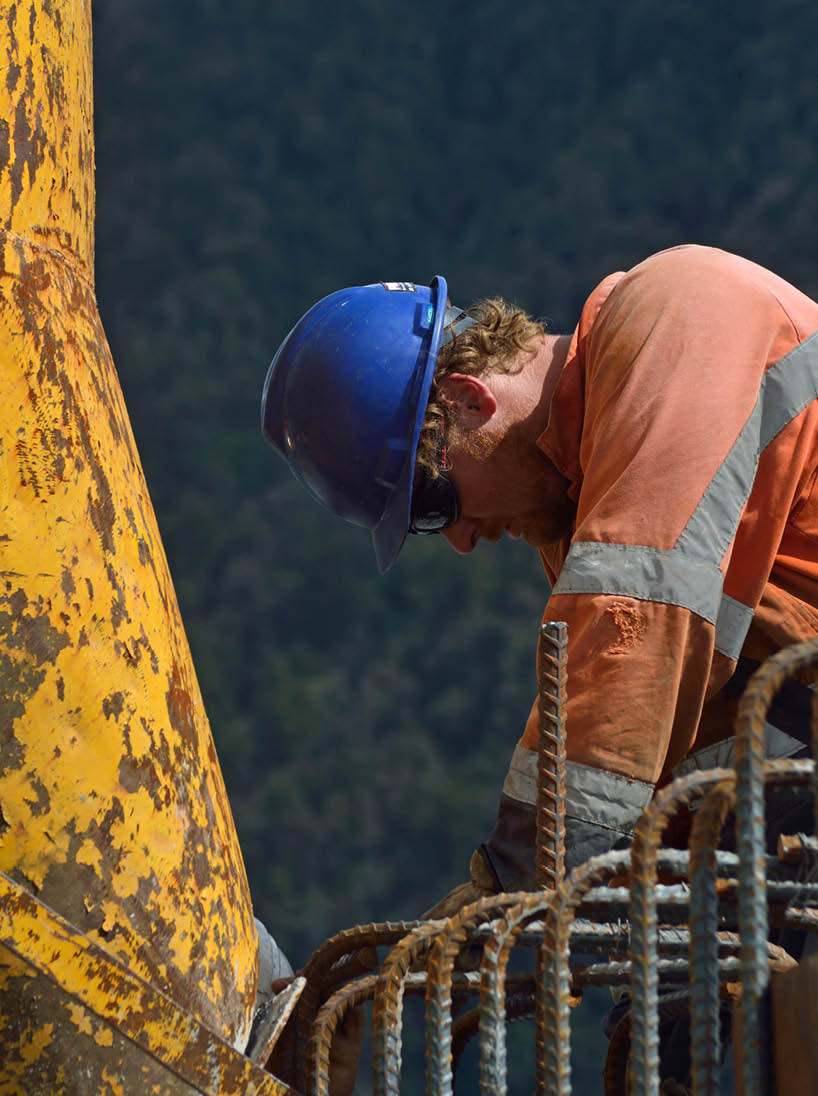 Builders construct a concrete bridge over a small river in Westland, New Zealand