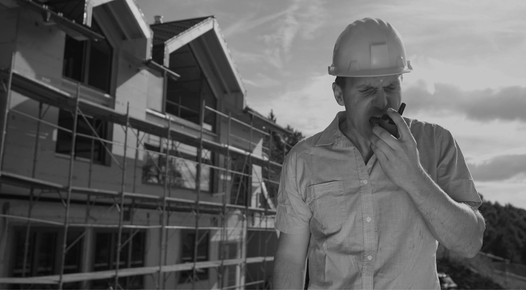 CLOSE UP: Angry Caucasian contractor shouts at his co-worker over the walkie talkie while standing outside of a house under construction  Raging architect gets into an argument with contractors 