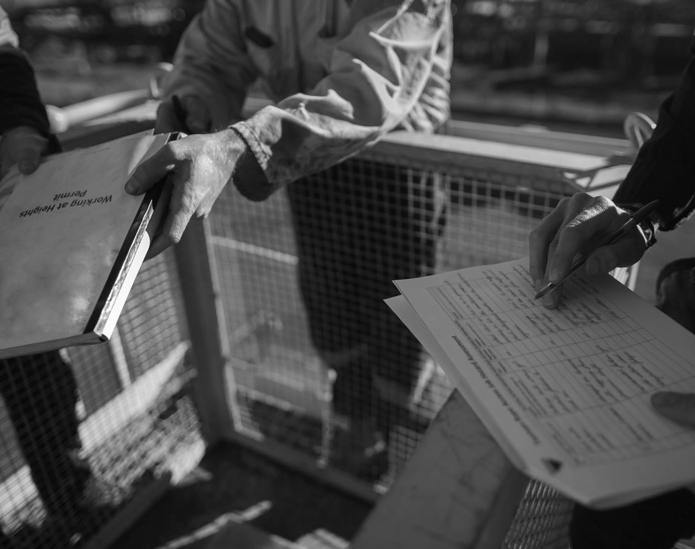 Trained supervisor competent checking reviewing document issued sign approvals of working at height permit JSA risk assessment on site prior to performing high risk work construction site, Australia 