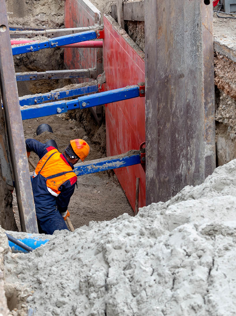 Worker making trench bed for new pipeline construction  Trench preparation for buried pipes  Keeping workers safe during trenching and excavation 