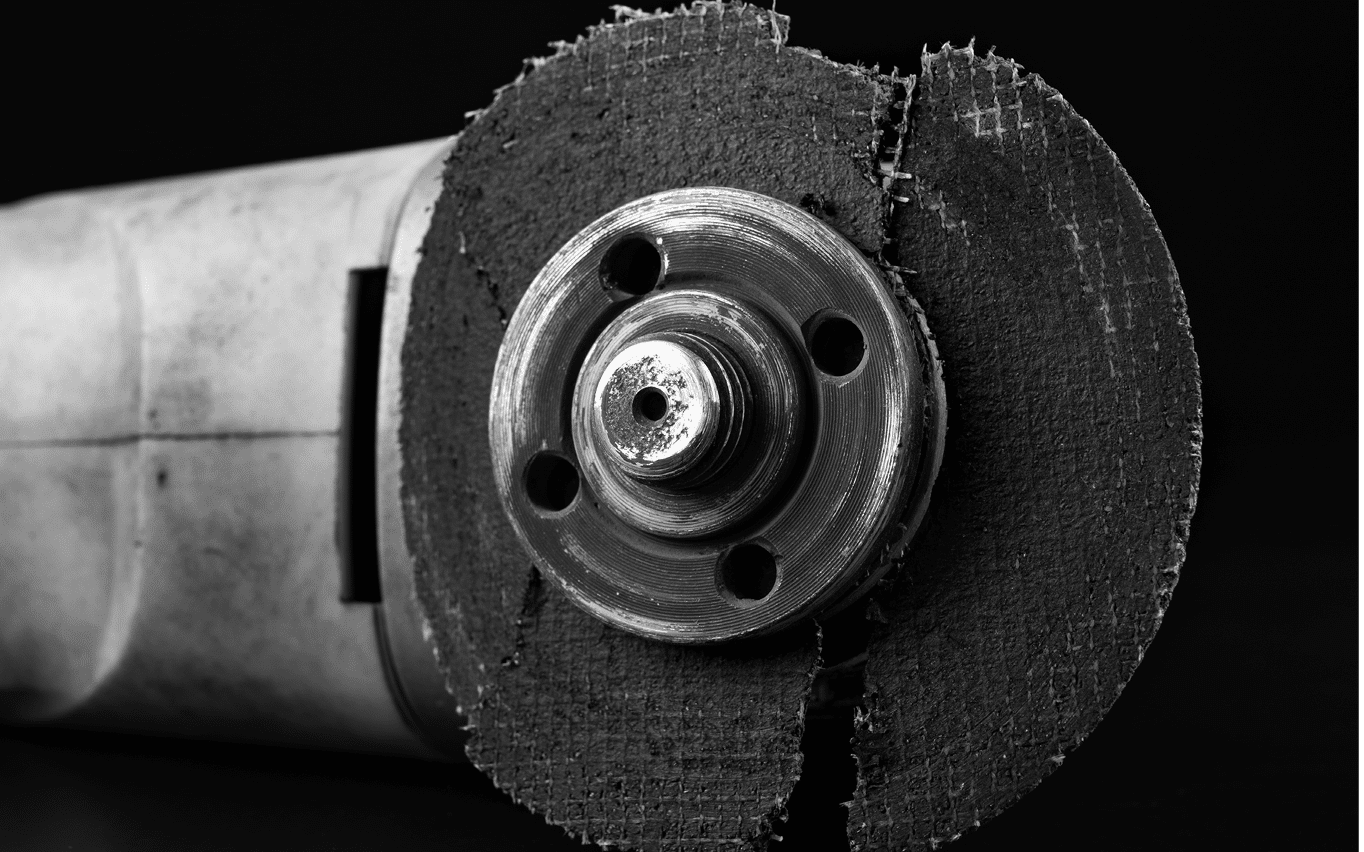 Damaged cutting disc for metal in an angle grinder  Power tools in a locksmith's workshop for repair  Dark background 